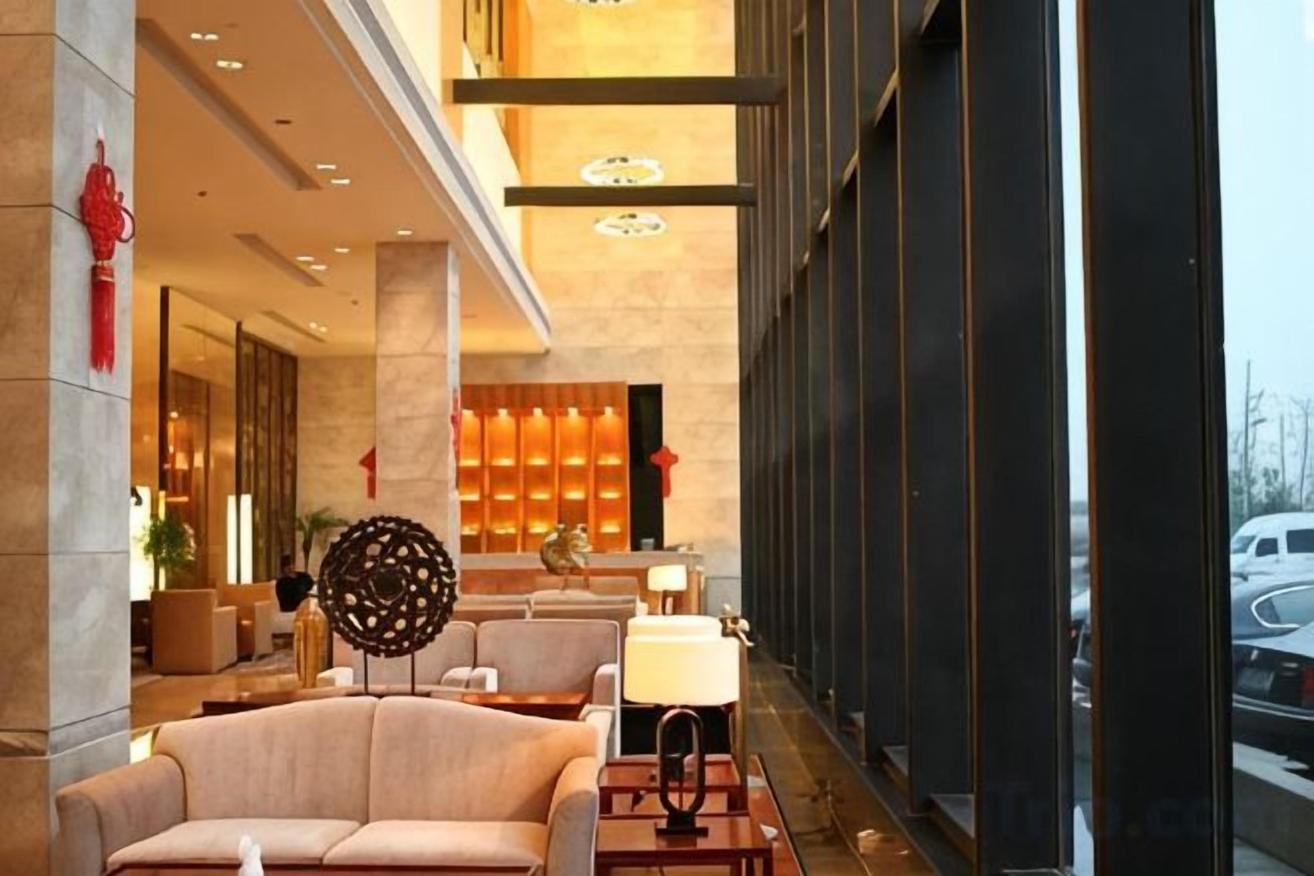 A hotel lobby with a seating area, a reception desk, and a large window.