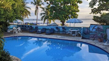 Una piscina al aire libre, sombrillas, sillones reclinables de piscina