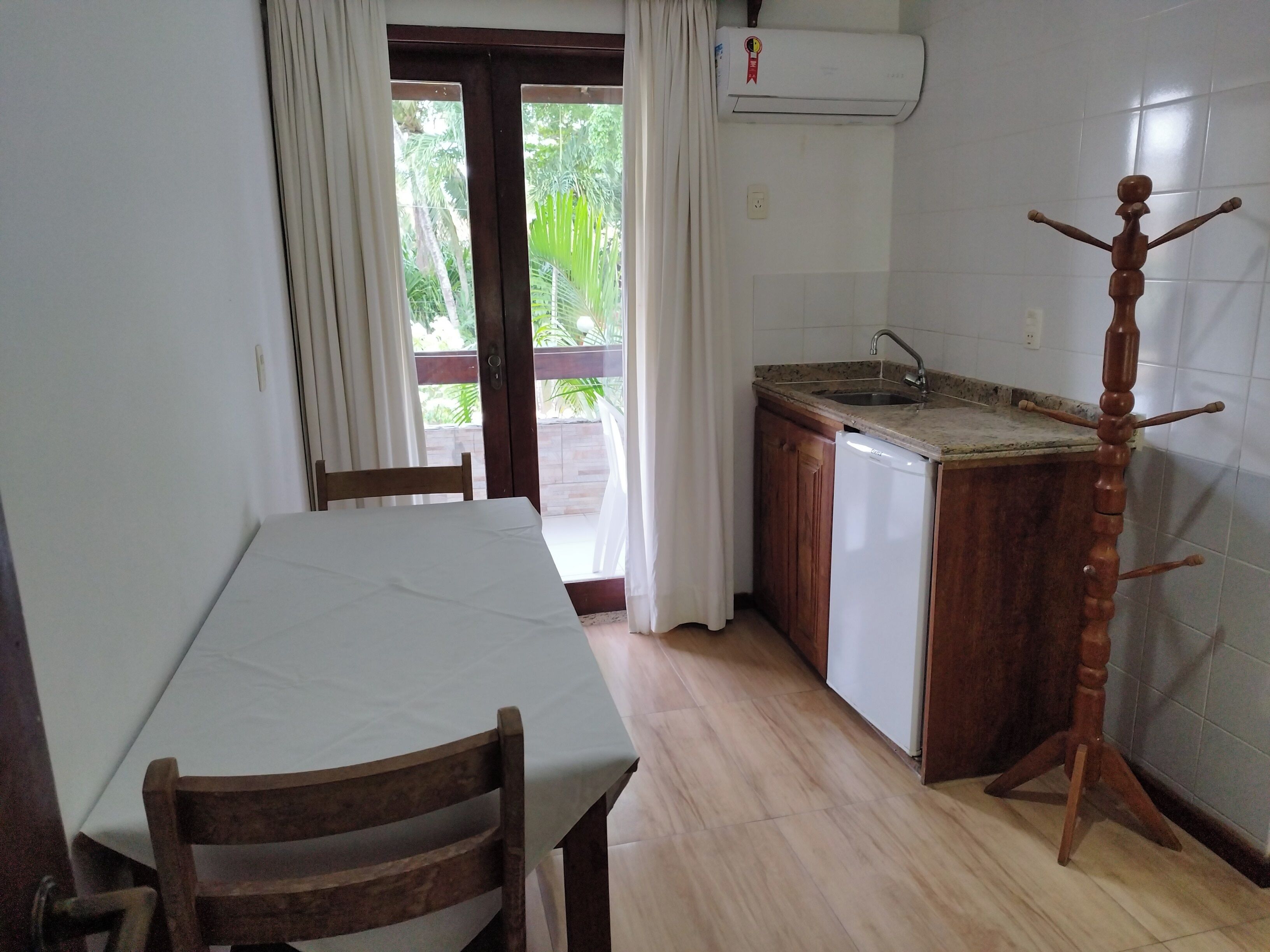 Une cuisine avec une table en bois, des chaises, un évier et un appareil de climatisation.