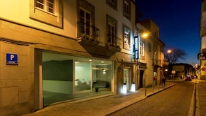 A hotel with a glass facade, a visible entrance, and a parking sign.