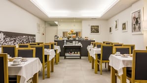A dining area with tables and chairs, a central counter with food items, and artwork on the walls.