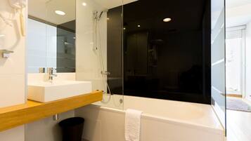 A modern bathroom with a white sink, a glass shower enclosure, and a bathtub.