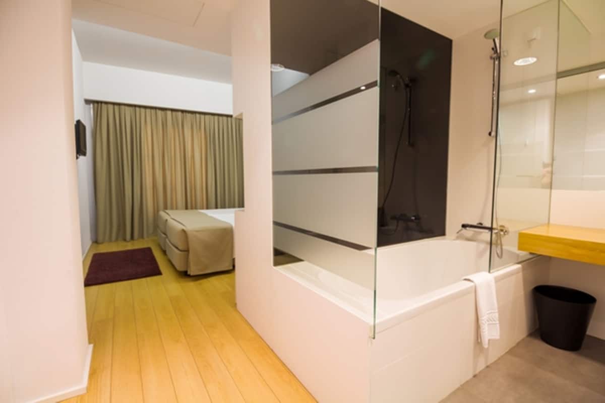 A modern bathroom with a glass-enclosed shower, a bathtub, and a wooden vanity.