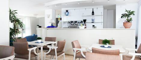 A modern kitchen with white cabinets, a coffee machine, and a potted plant.