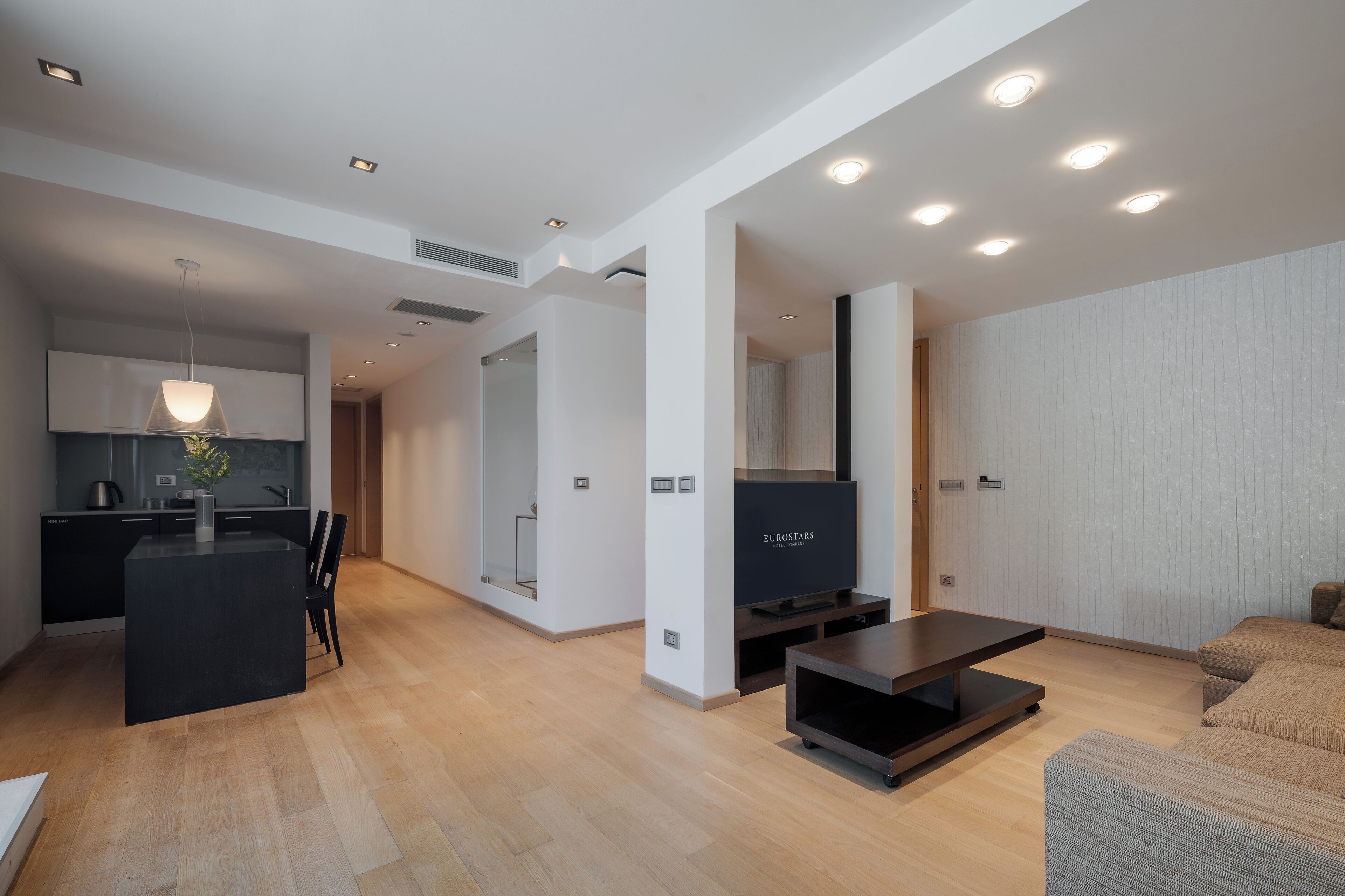 A modern living room with a flat-screen TV, a dark coffee table, and a sofa.