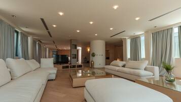 A modern living room with a large sectional sofa, a glass coffee table, and a flat-screen TV.