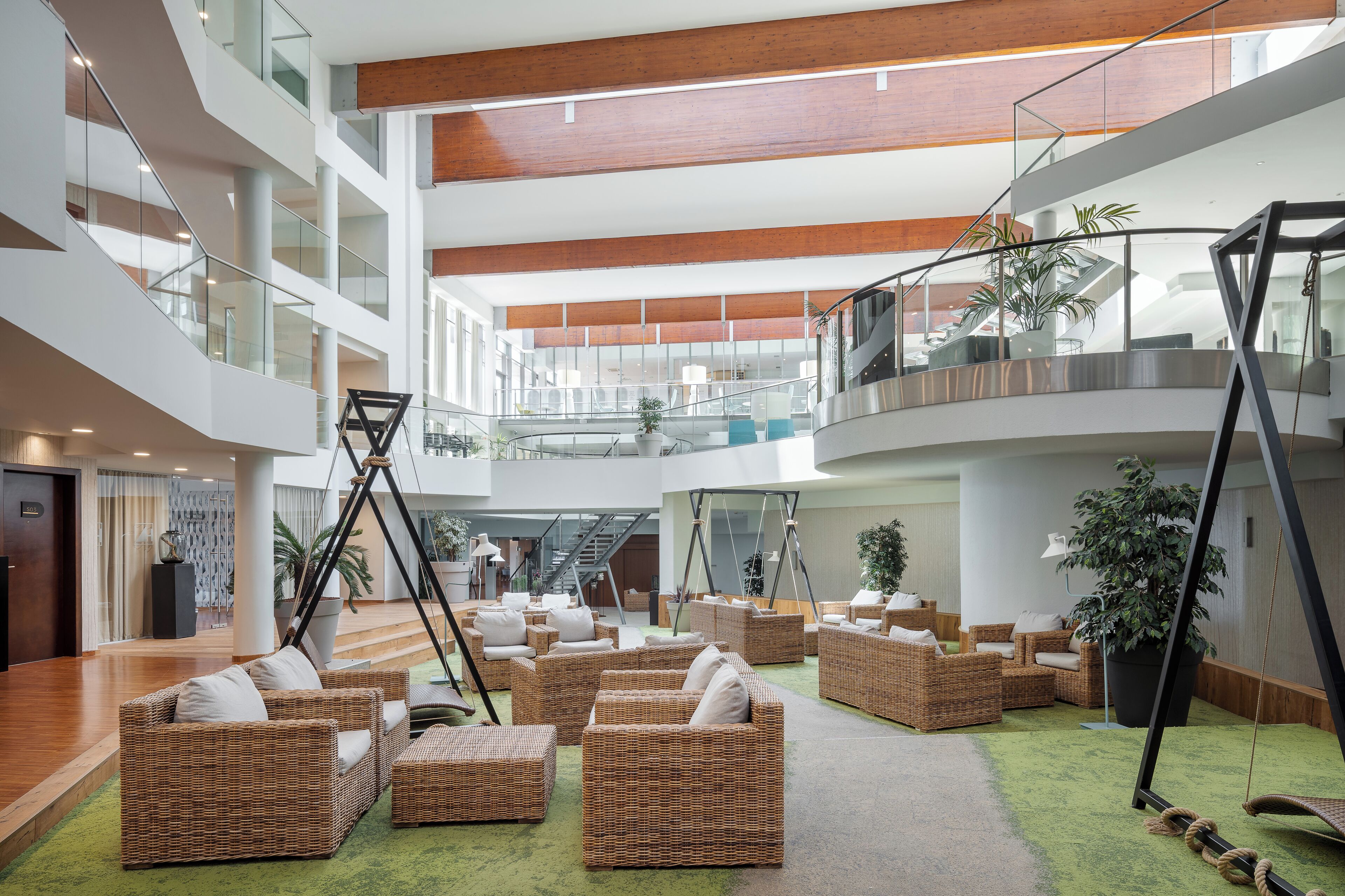 A spacious lobby with wicker furniture, a staircase, and a large plant.