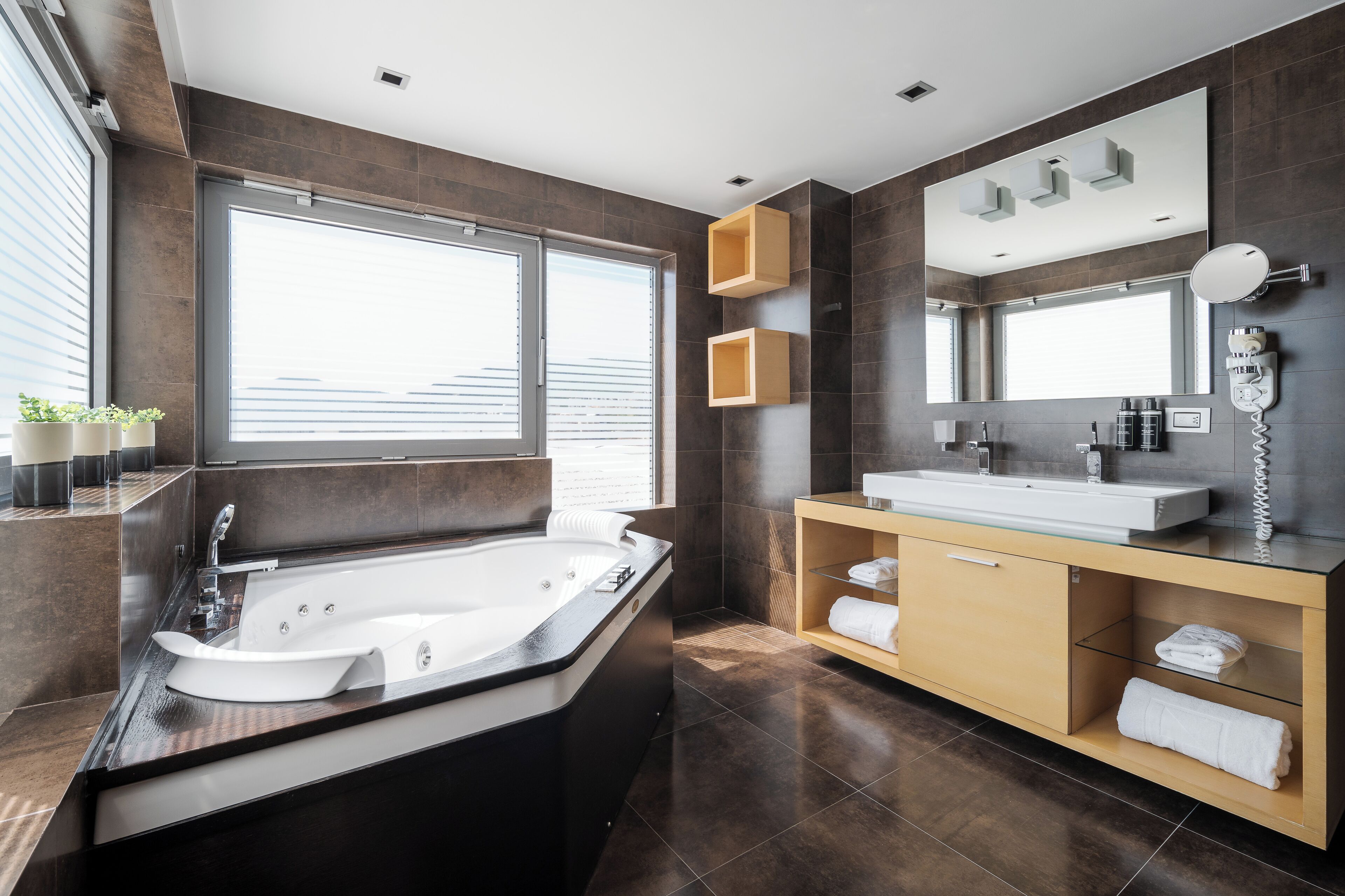 Ein modernes Badezimmer mit einer großen Badewanne, einem Waschtisch mit Spiegel und einem Fenster für natürliches Licht.