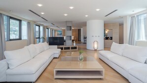 A modern living room with a large sectional sofa, a glass coffee table, and a flat-screen TV. - Eurostars Queen of Montenegro (Becici)