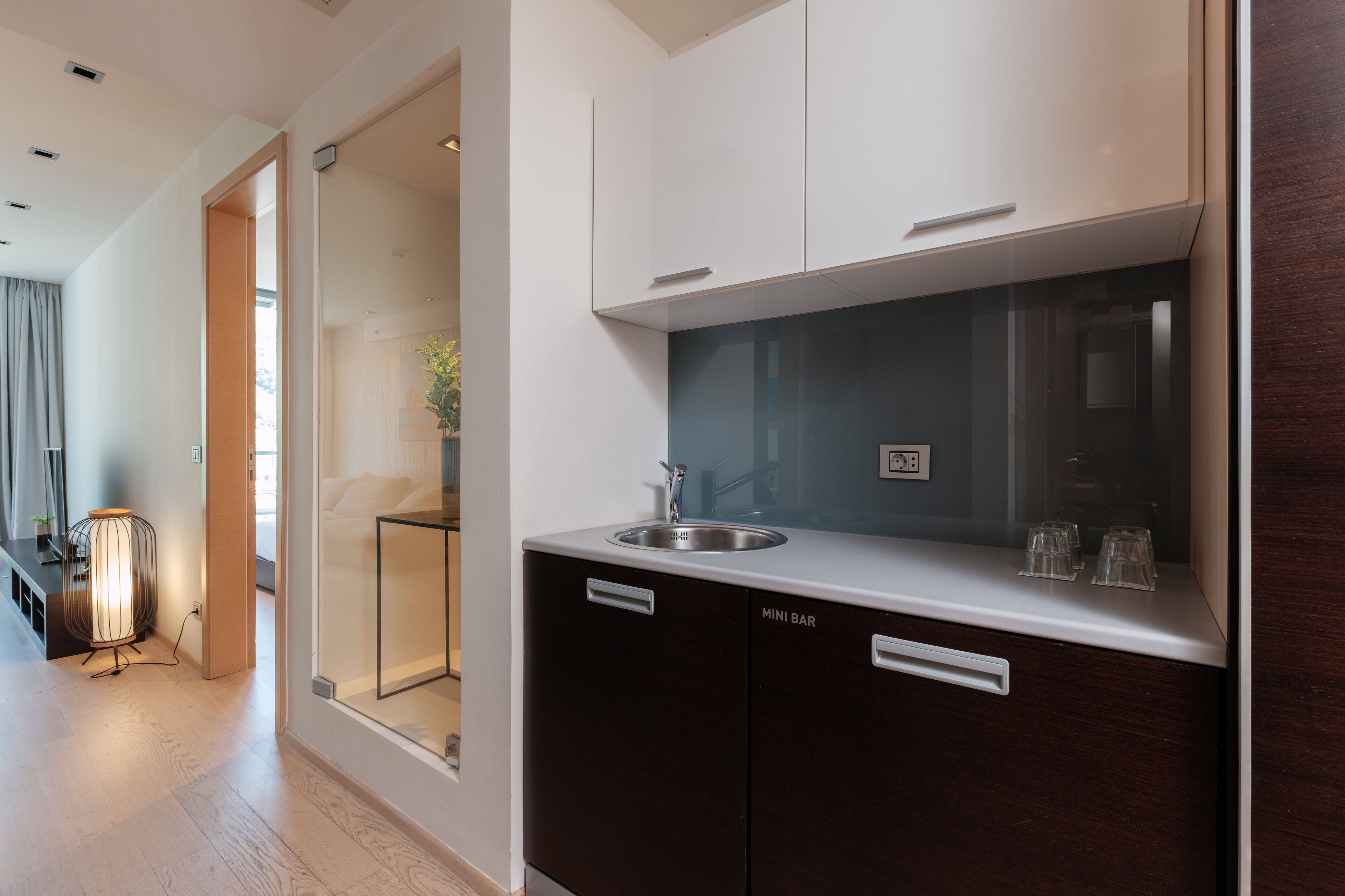 Eine moderne Küche mit eingebautem Spülbecken, einer Minibar und einem Schrank mit Glastür.