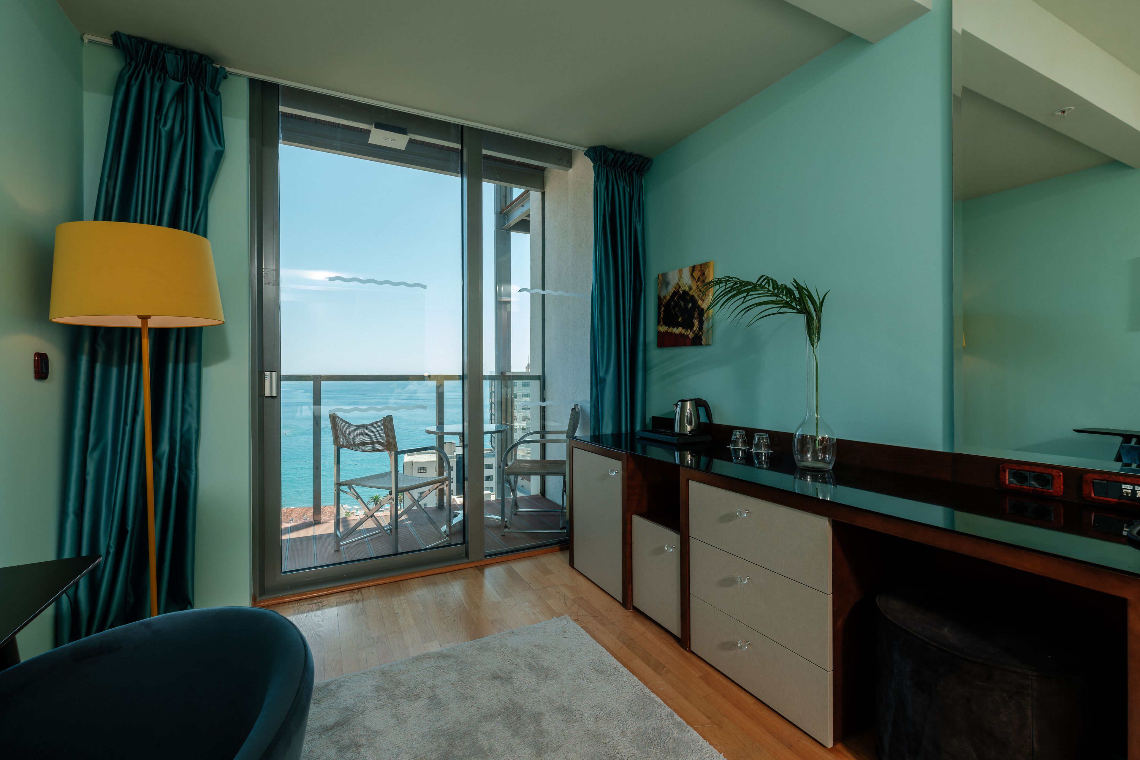 Una cocina moderna con vista al mar, un comedor con una silla y un gran ventanal con cortinas.