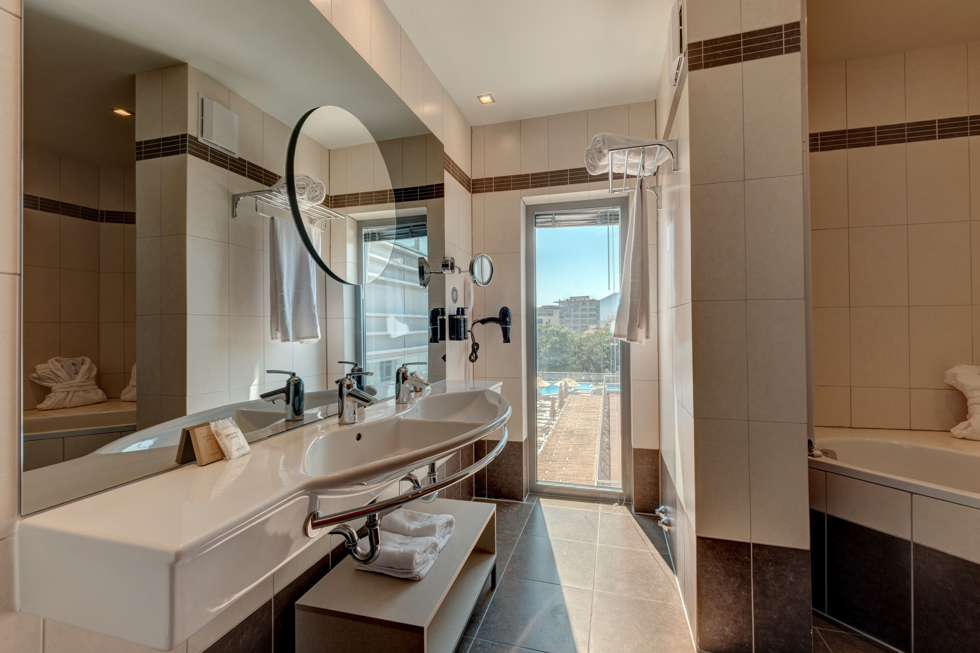 A modern bathroom with a large sink, mirror, and bathtub.
