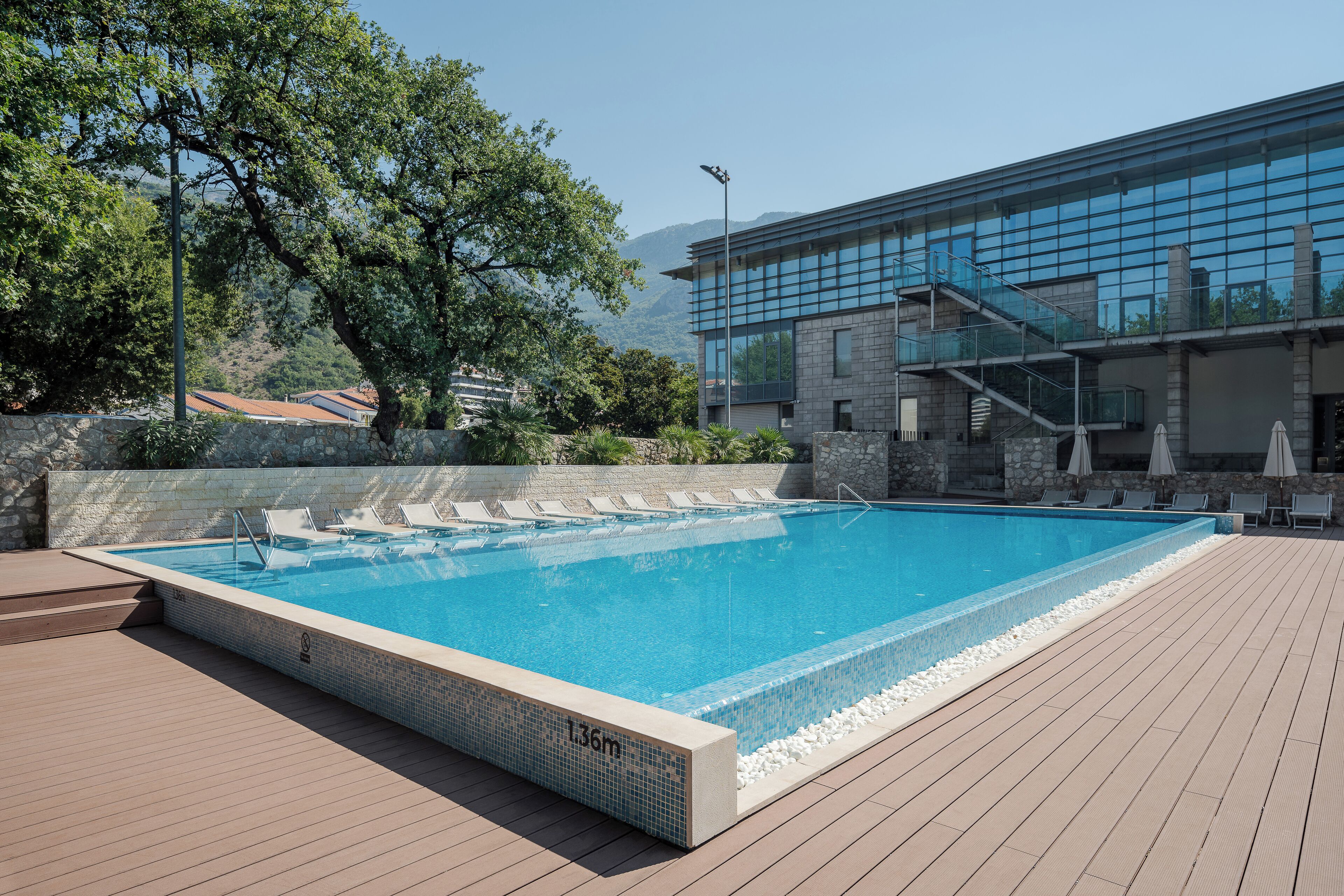 Una piscina rectangular con borde de azulejos y un indicador de profundidad que marca 1,36 metros.