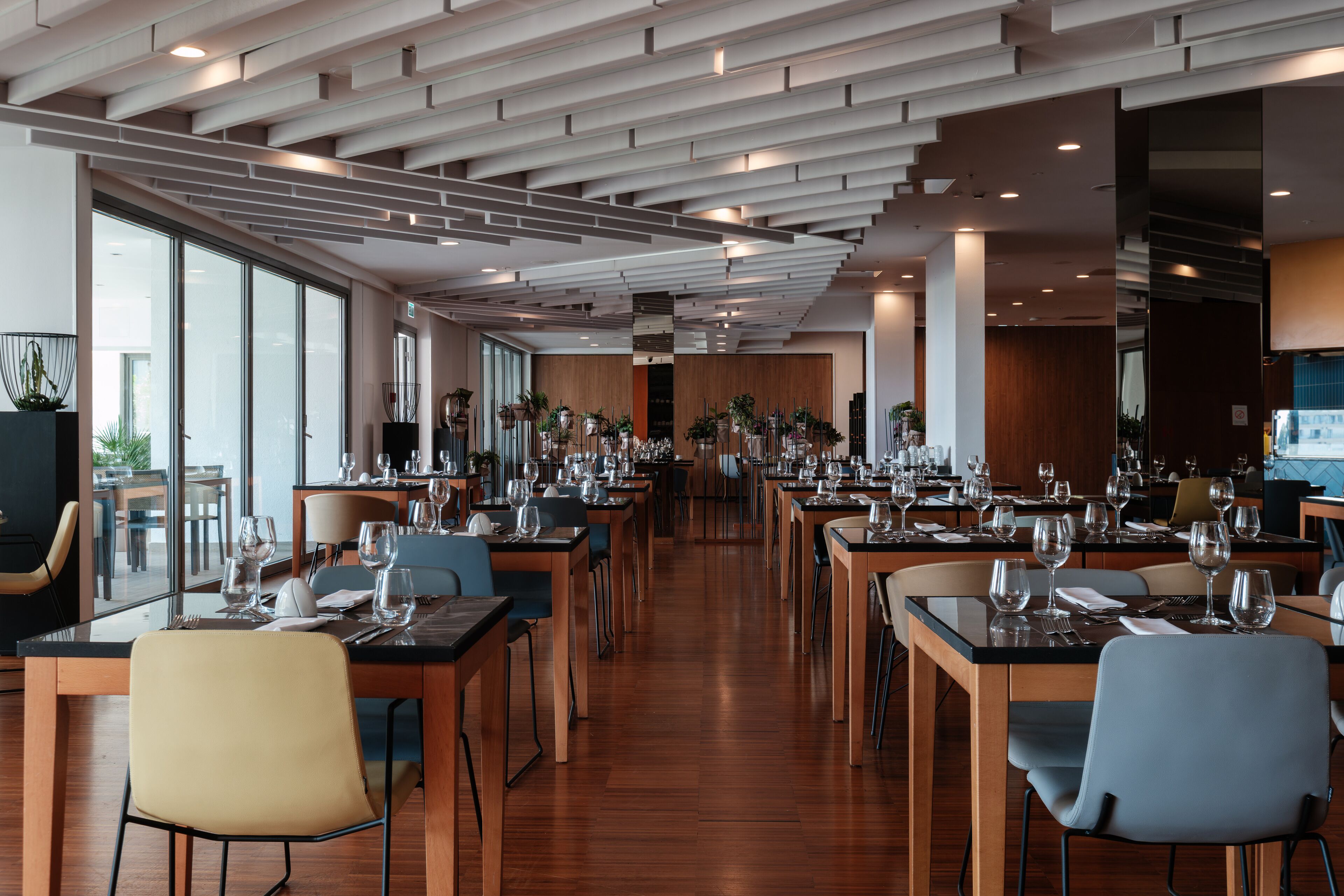 Un restaurante moderno con mesas largas, sillas y piso de madera.