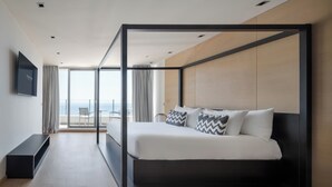 A modern bedroom with a bed in a black frame, a flat-screen TV on the wall, and a view of the sea through large windows. - Eurostars Queen of Montenegro (Becici)