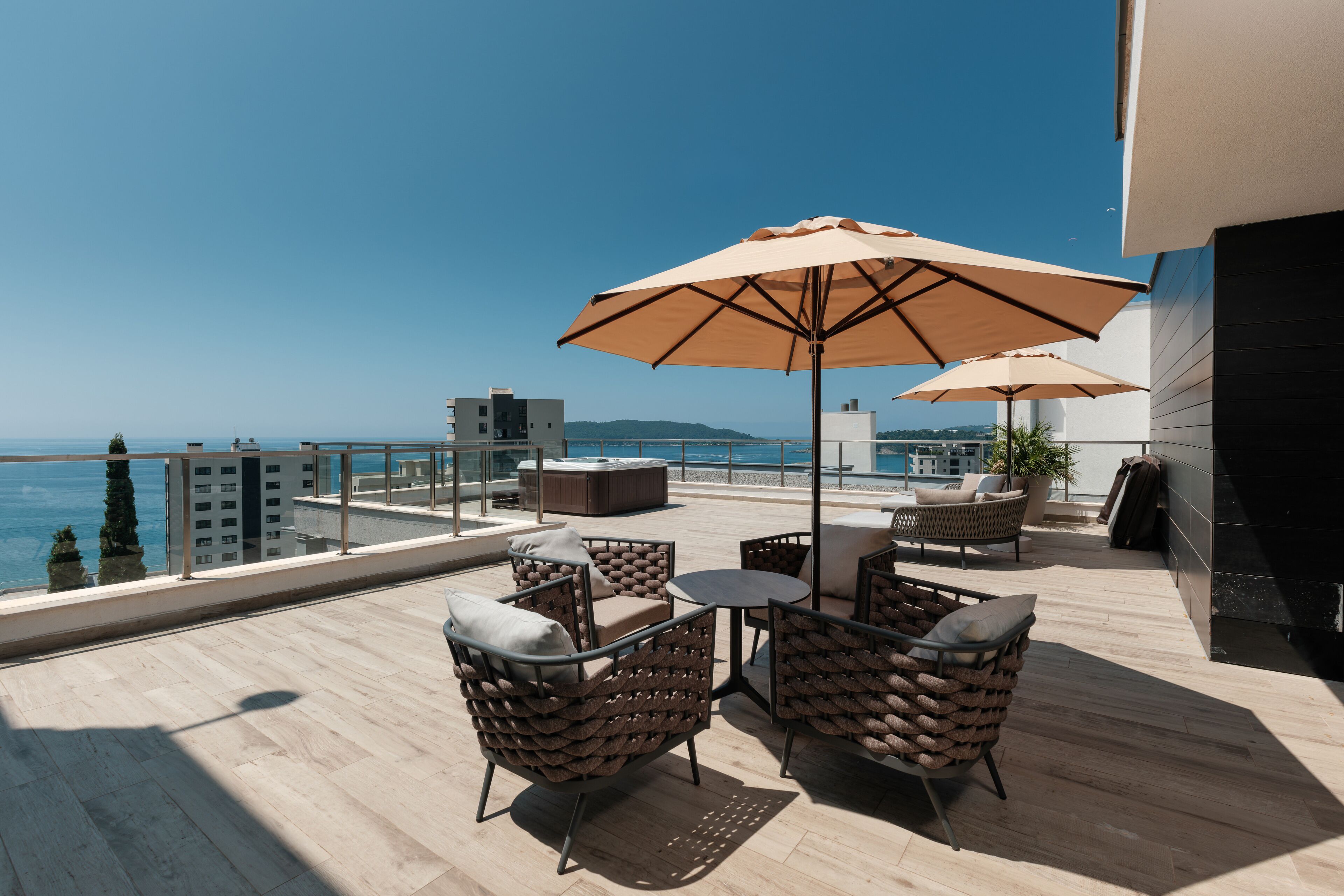 En tagterrasse med udendørs møbler, et spabad og havudsigt.
