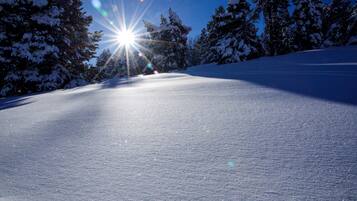 A snow-covered slope with a clear sky and sunlight.