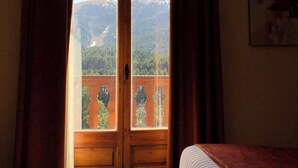 A room with a bed, a window with curtains, and a painting on the wall.