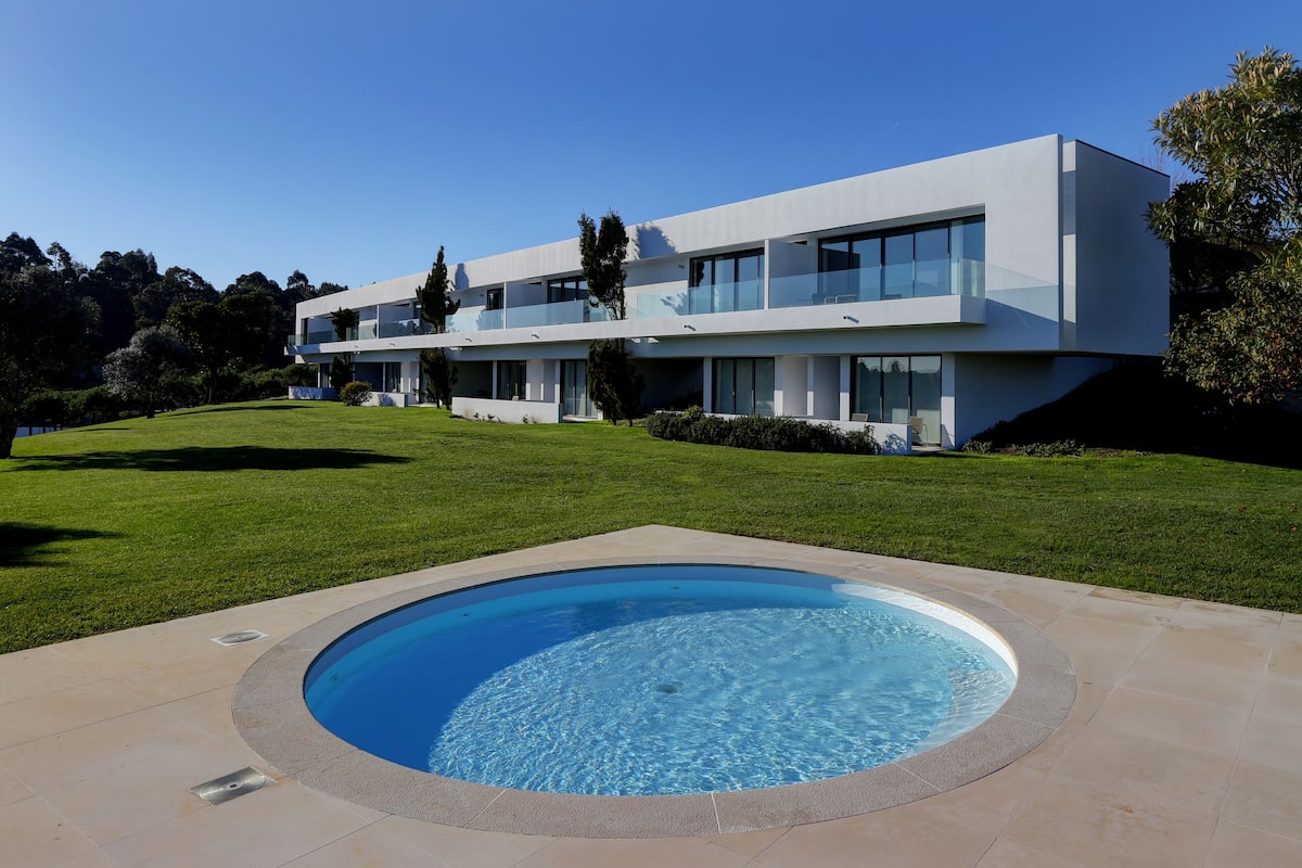 Une maison moderne à deux étages avec une piscine située dans le jardin avant.