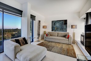 A modern living room with a large window, a sofa, a coffee table, and a fireplace. - Bom Sucesso Resort (Obidos)