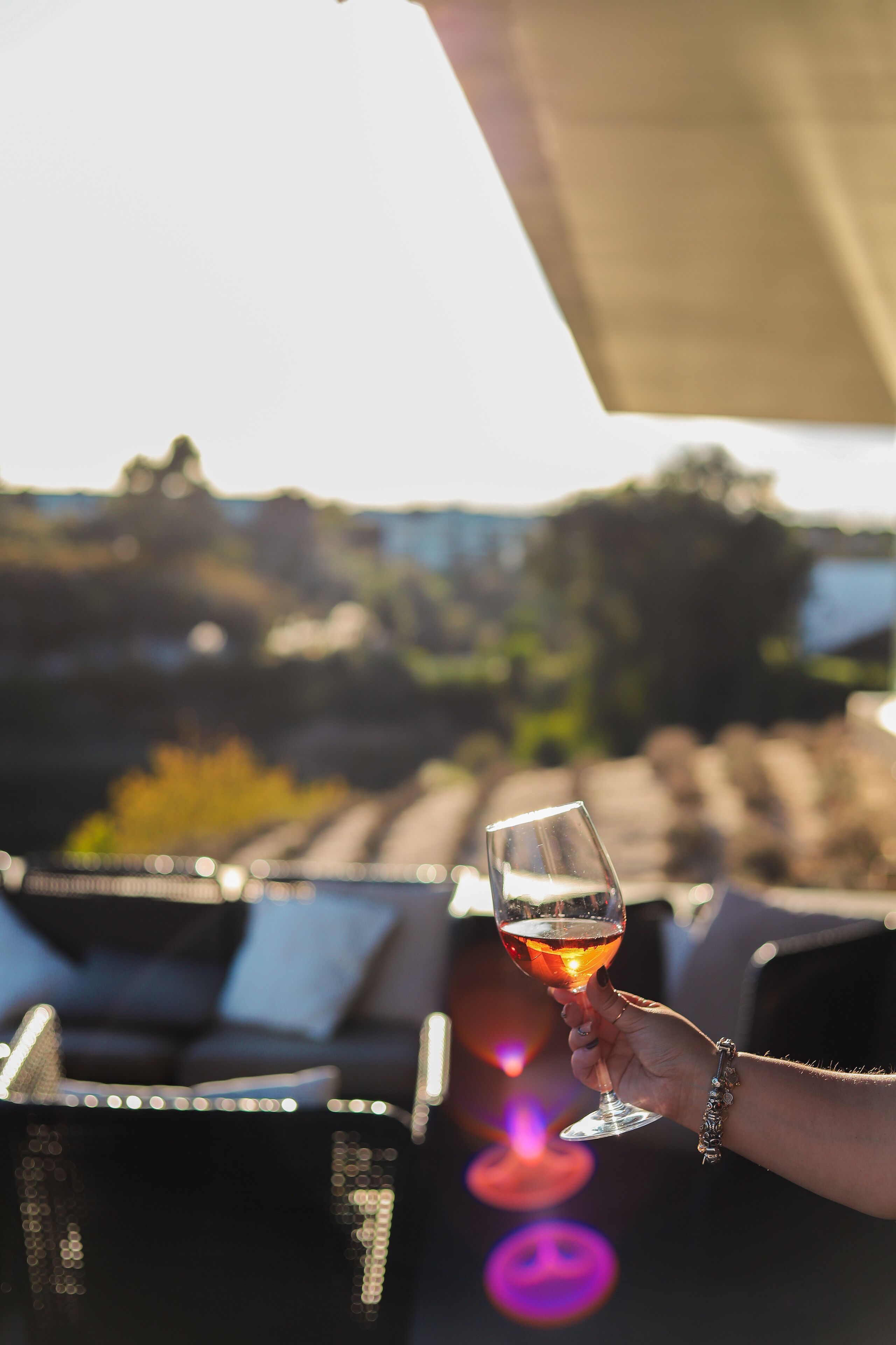 A person holding a glass of wine with a blurred outdoor background.