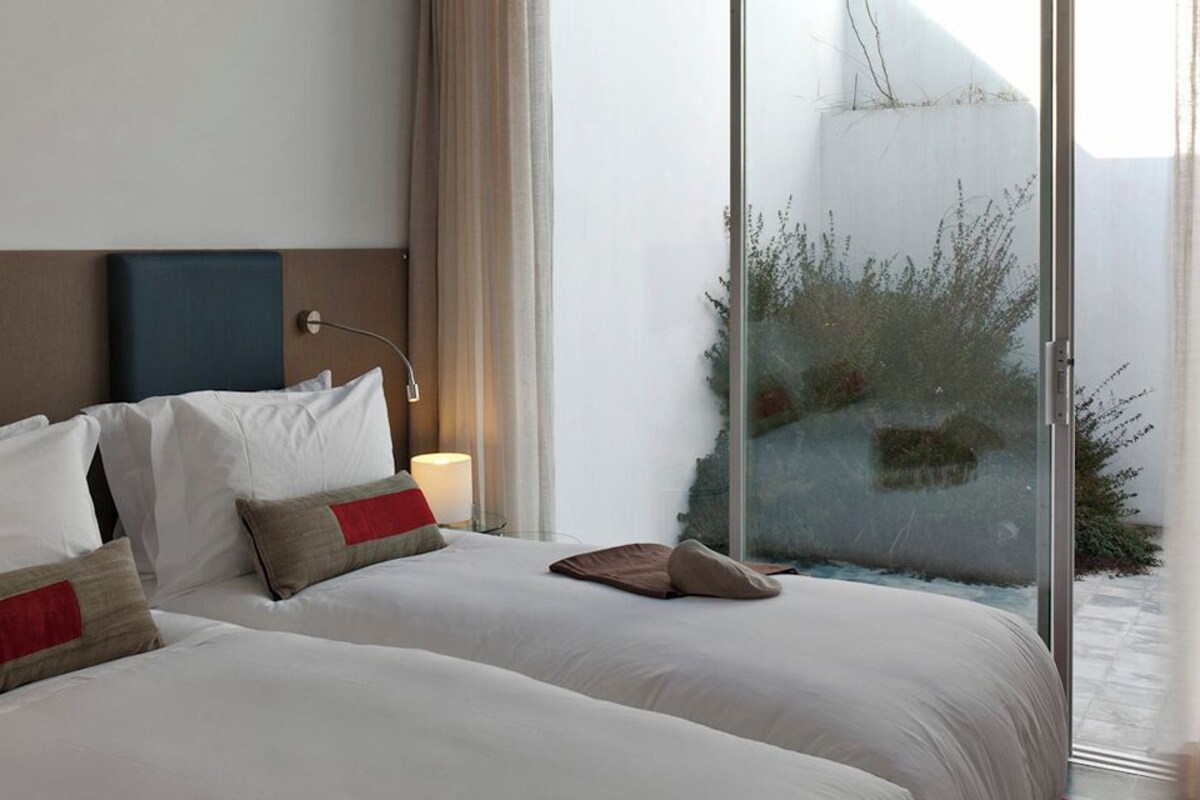 A hotel room with two beds, a TV, and a large window with a view.
