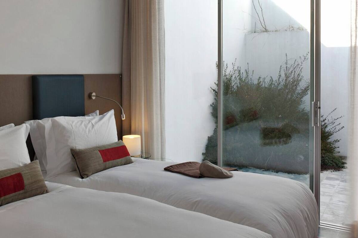 A hotel room with two beds, a TV, and a large window with a view.