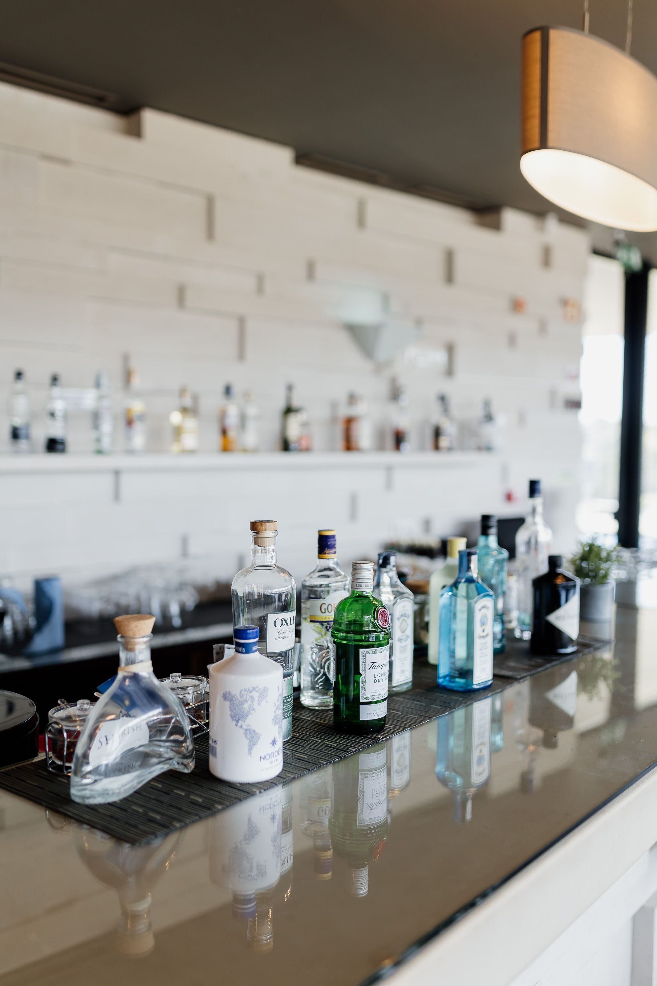 Un espace bar avec différentes bouteilles d’alcool et des verres disposés sur un comptoir réfléchissant.