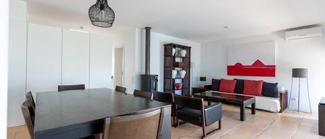 A modern living room with a dining area, featuring a sofa set, a coffee table, and a dining table with chairs.