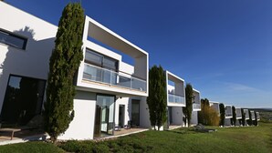 Una casa moderna de dos pisos con ventanas amplias, un balcón y un jardín cuidado.