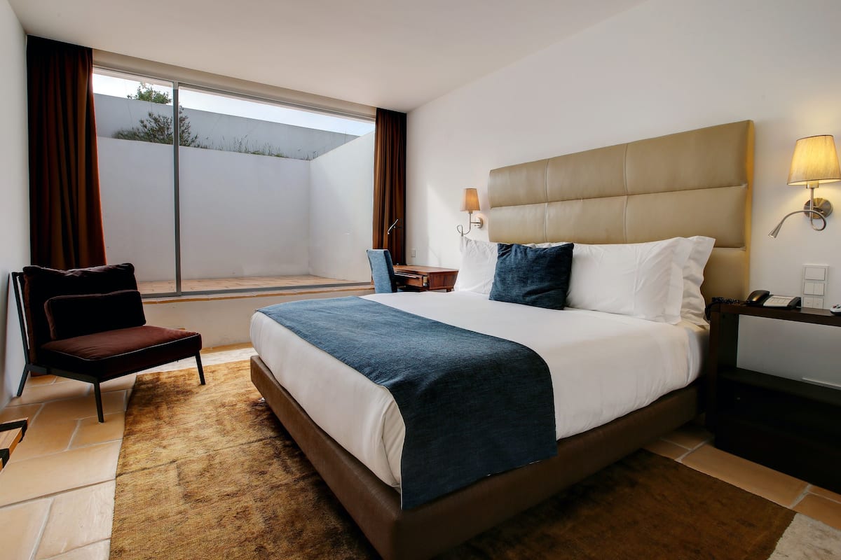 Une chambre d’hôtel moderne dotée d’un grand lit, d’un bureau, d’une chaise et offrant une vue sur l’extérieur.