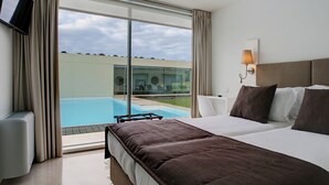 Habitación de hotel con una cama grande, televisión, vista a una piscina y ventana con cortinas.