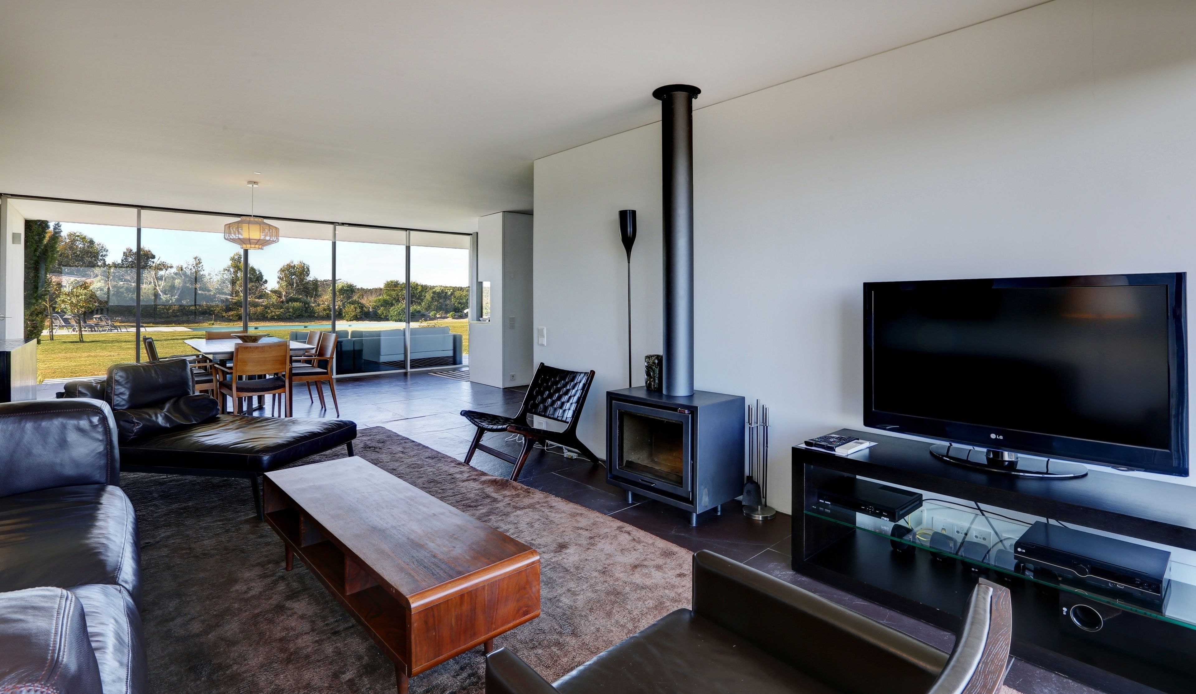 Una sala moderna con un televisor grande, chimenea y vistas al exterior.
