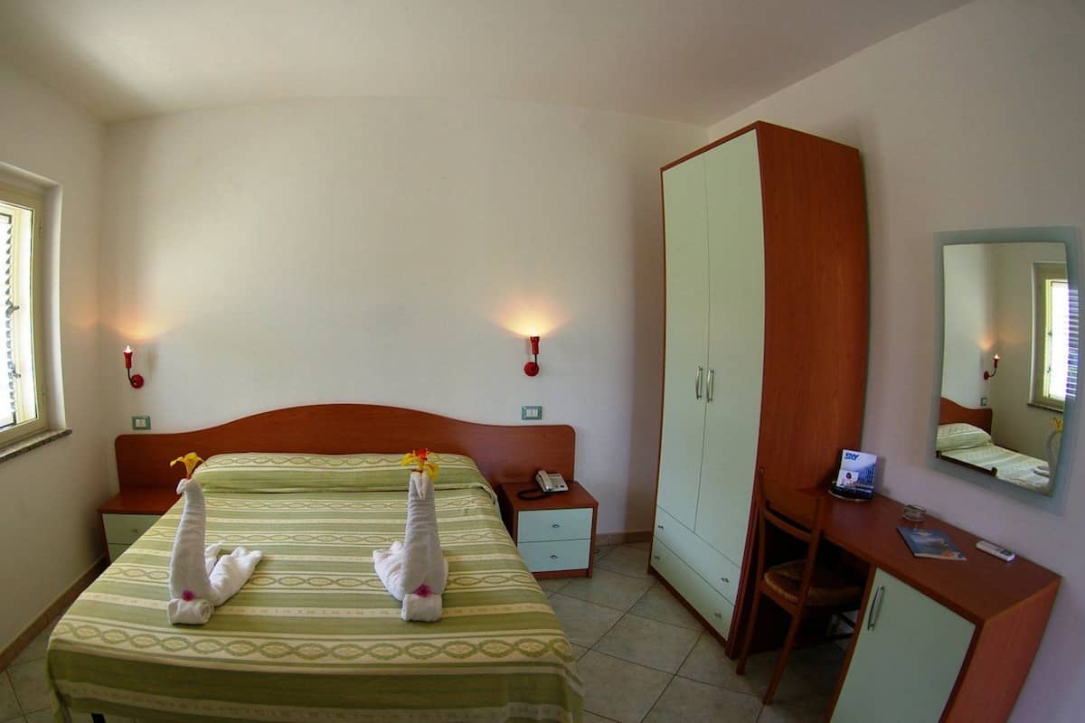 Ein Hotelzimmer mit Bett, Schreibtisch, Kleiderschrank und Spiegel.