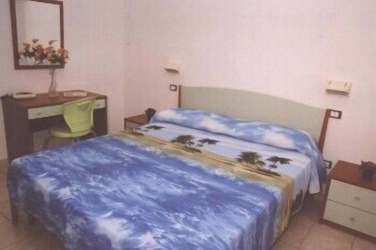 Ein Schlafzimmer mit Bett, Schreibtisch, Stuhl und Nachttisch.