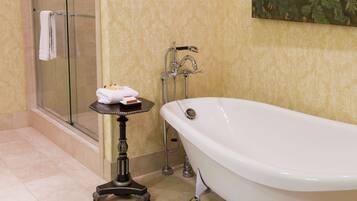 Un bagno con doccia vetro, vasca da bagno bianca e un tavolino con articoli da toilette.