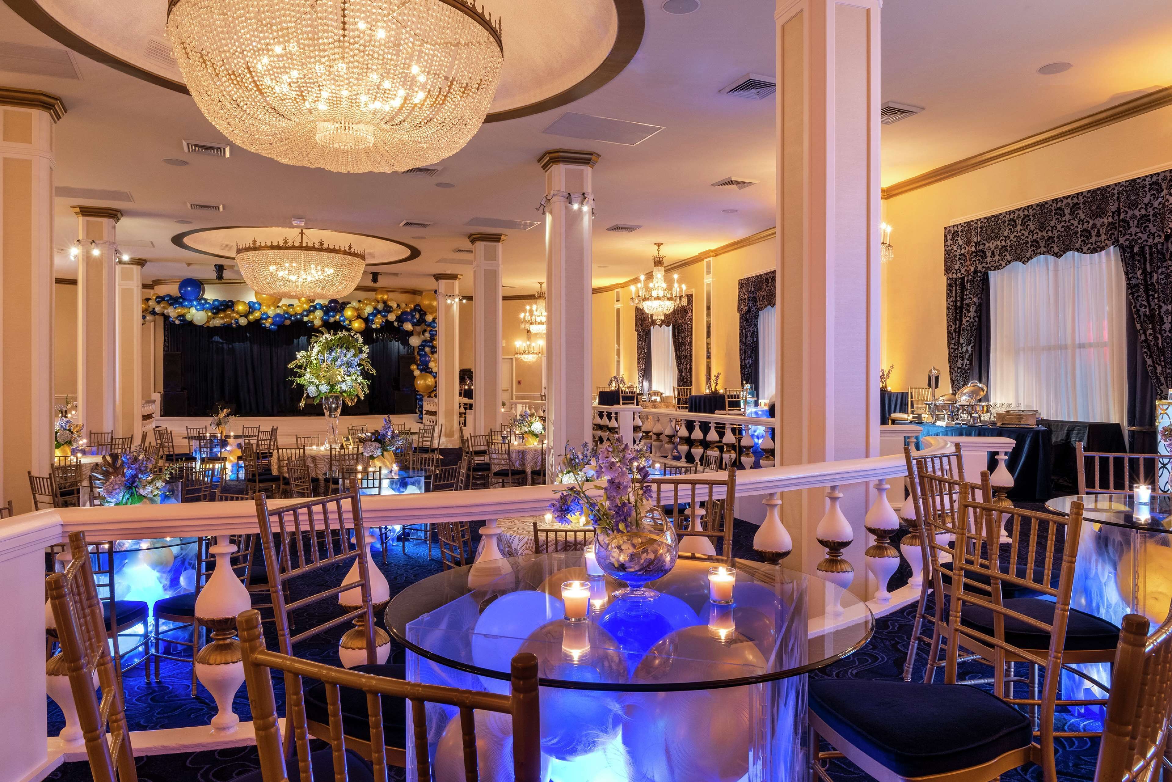 Un elegante comedor con mesas redondas, sillas, candelabros y adornos florales.