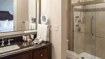 A modern bathroom with a large mirror, a sink with multiple faucets, a toilet, and a glass-enclosed shower.