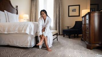 Una habitación de hotel con cama, una silla, tocador y lámpara.
