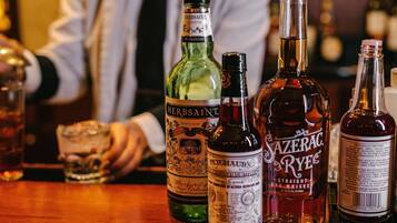 Eine Bar mit verschiedenen Spirituosenflaschen, darunter 'Herbsaint' und 'Sazerac Rye'.