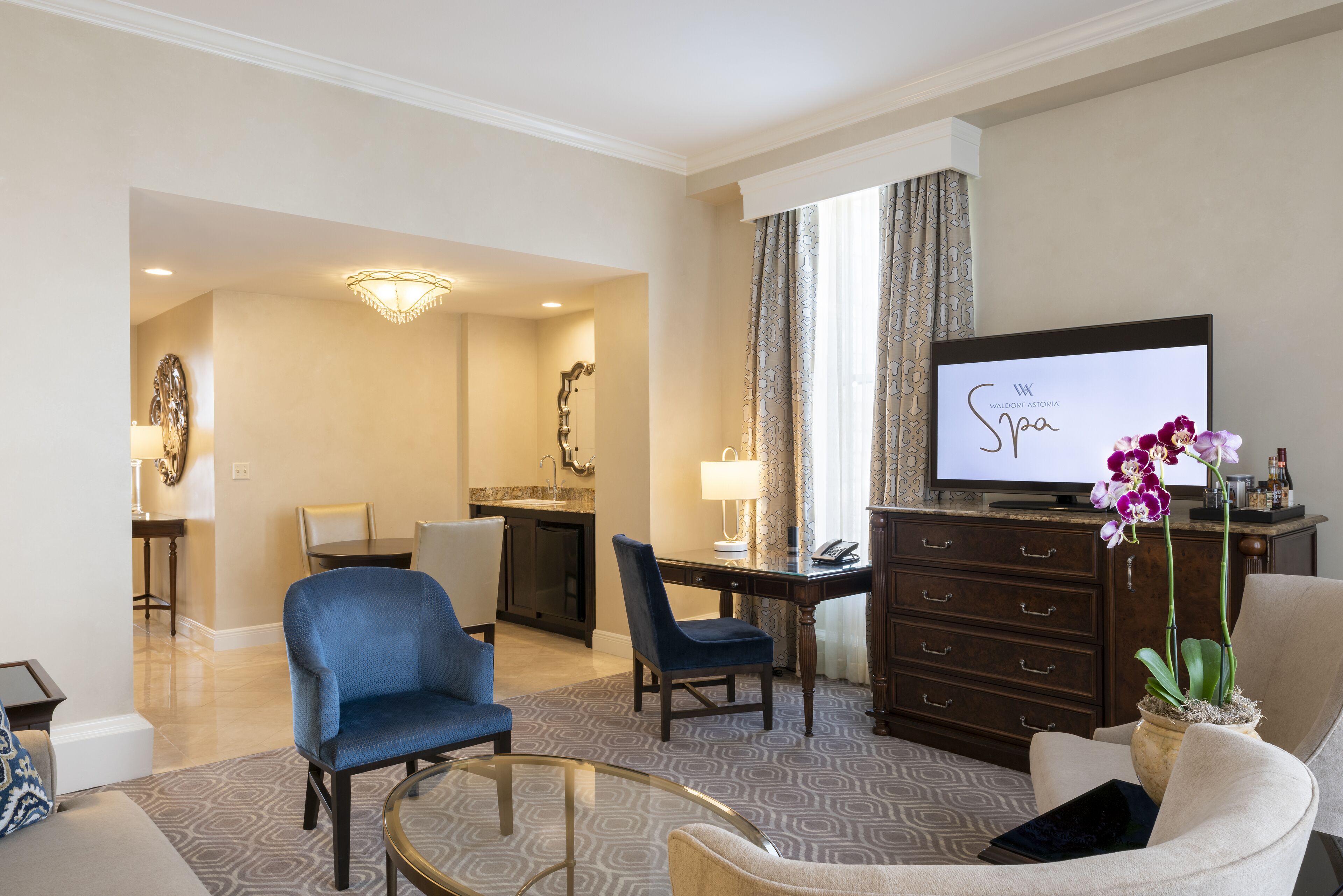 Quarto de hotel com área de refeições, televisão e sofá.