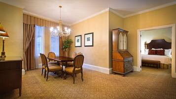 A hotel room with a dining area, a large wooden cabinet, and a bed with a headboard.
