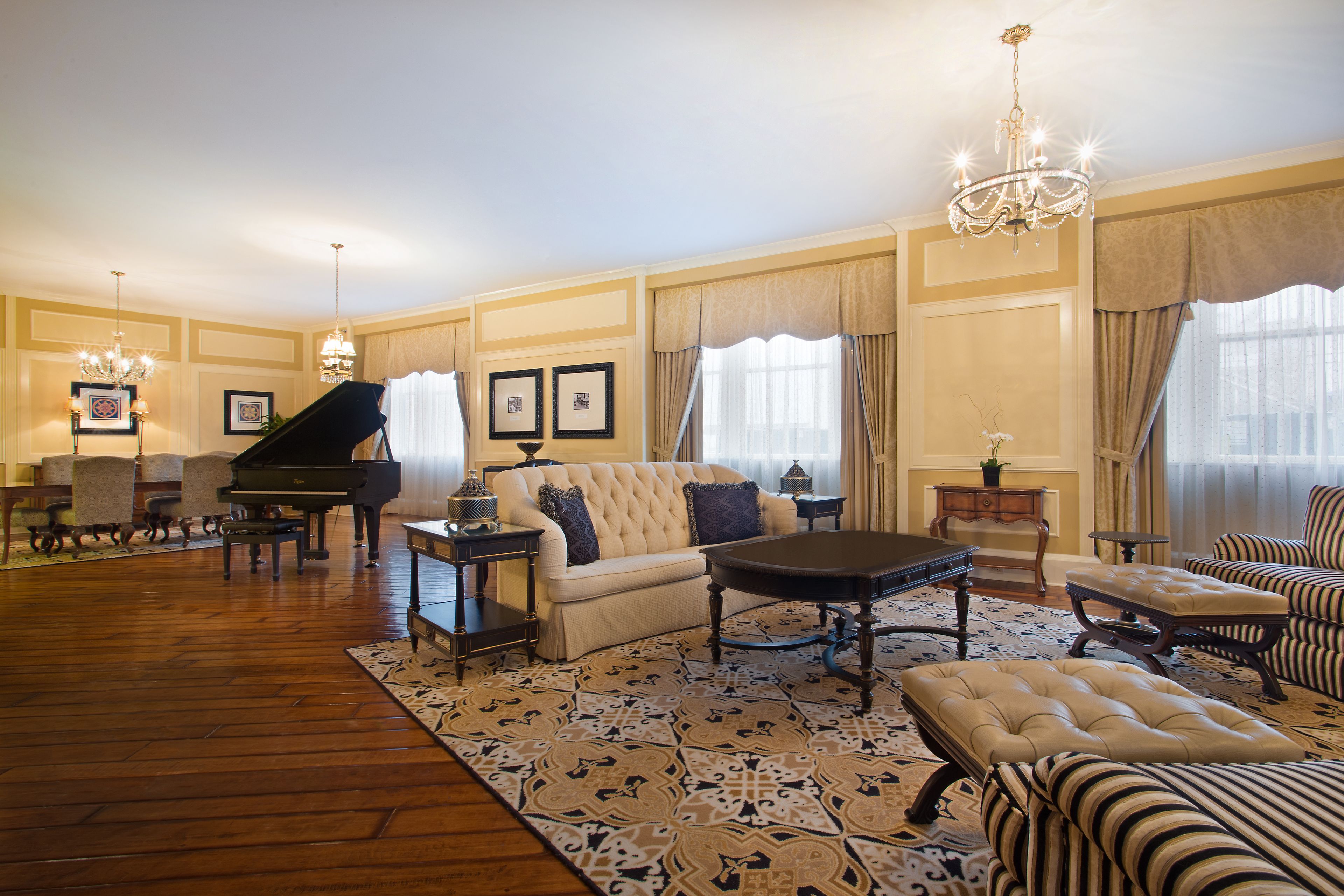 Uma sala de estar ampla com um piano de cauda, um sofá, uma mesa de centro e poltronas listradas.