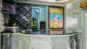 Una zona de recepció amb un taulell de vidre, un quadre religiós emmarcat, un panell informatiu digital i una estàtua decorativa daurada.