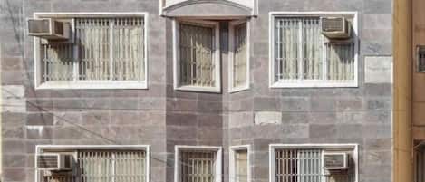 A building with multiple windows, each with metal bars and air conditioning units.