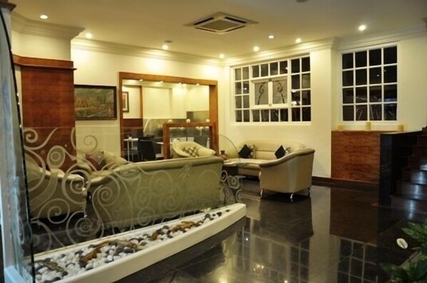 A spacious living area with a sofa, armchairs, a coffee table, and a decorative fish pond.