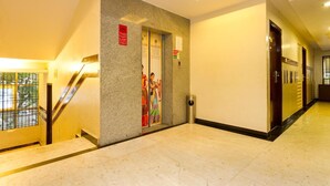 A hotel lobby with a marble floor, a staircase, and a door with a poster. - Golden Residency (Bengaluru)