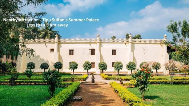 A large, white building with a symmetrical facade, surrounded by well-manicured gardens and palm trees. - Golden Residency (Bengaluru)