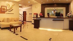 A hotel reception area with a reception desk, a sofa, and a coffee table. - Golden Residency (Bengaluru)