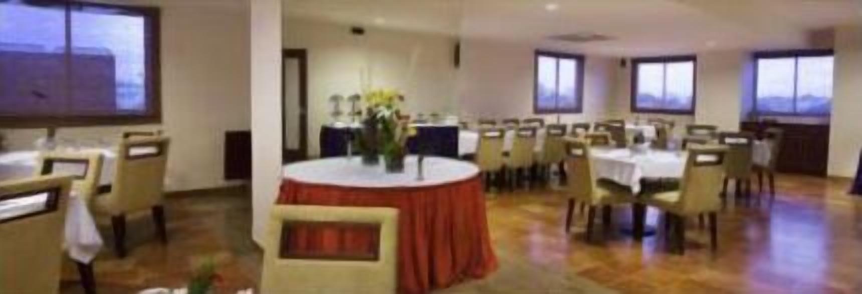 Un salón de conferencias con mesas redondas, sillas y un escenario con un atril.